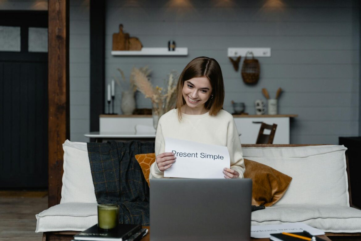 woman sitting in front of a laptop holding a paper