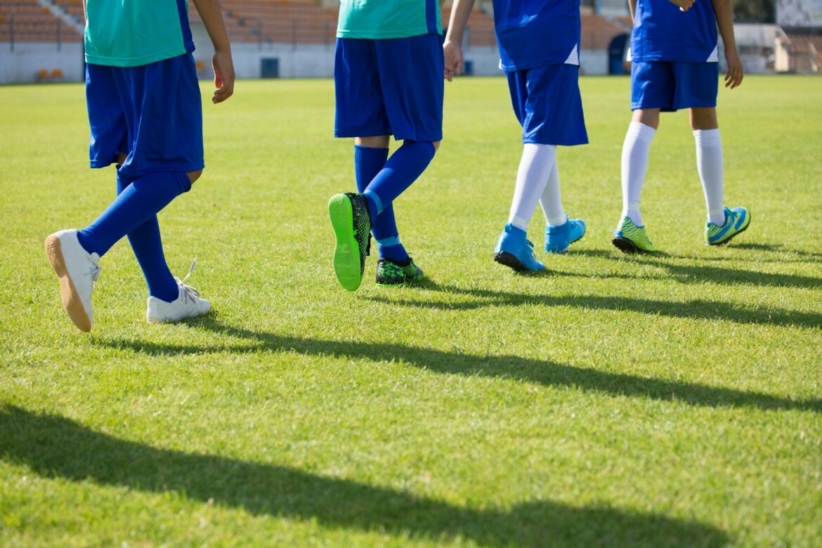 children in uniform walking on a green grass field