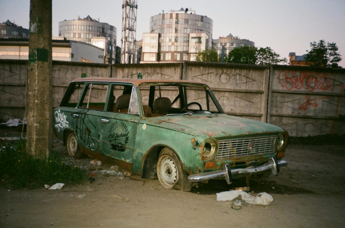 photo of abandoned green car beside post