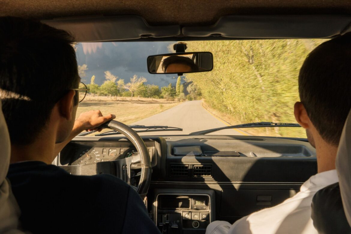 two men driving in a car on a road